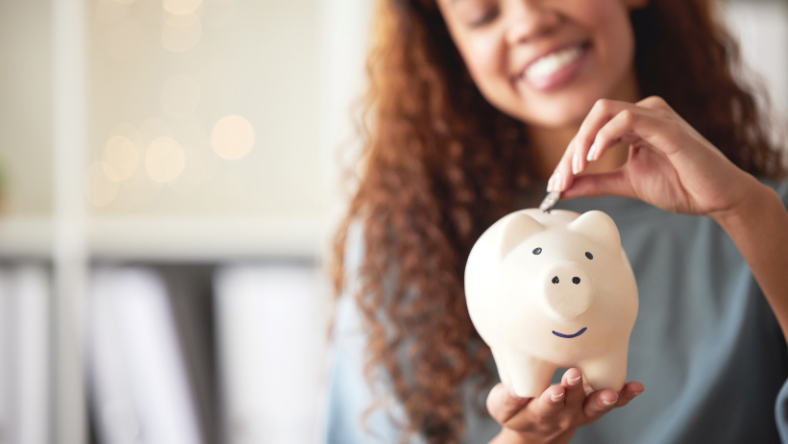 Smiling woman putting coins into piggy bank