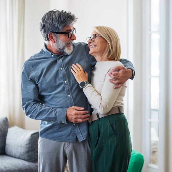 Two adults standing together in a home setting while discussing future financial goals and retirement planning.