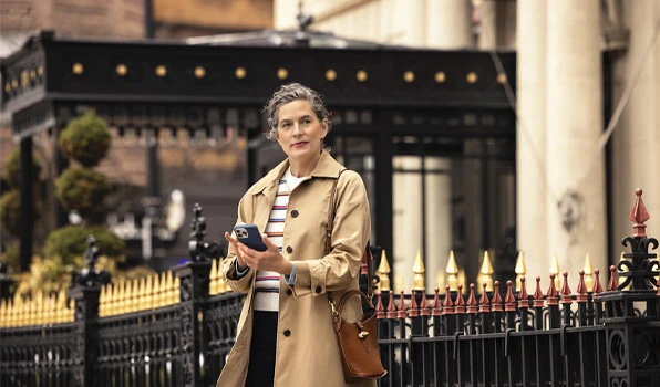 Customer using a smartphone while walking in an urban setting, illustrating convenient access to mobile banking, account management, and financial services through Club Five.