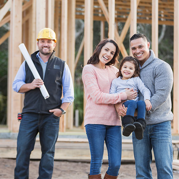 Father, son and young daughter standing in front of new home construction with builder