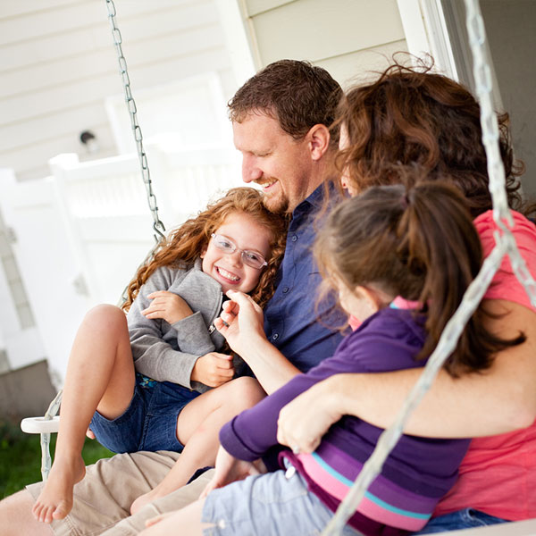 Happy parents and young girls on porch swing