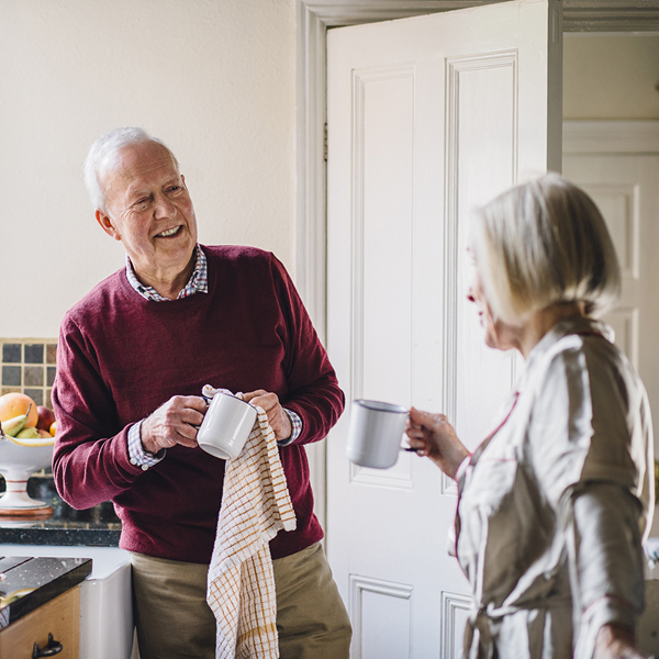 Happy older couple in kitchen drinking coffee